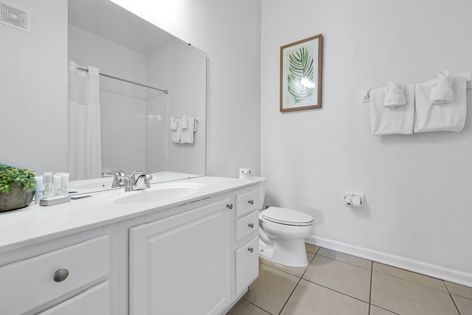 Step into your crisp, bright bathroom with a full tub-shower combo, generous vanity space, and fresh white towels awaiting your arrival.