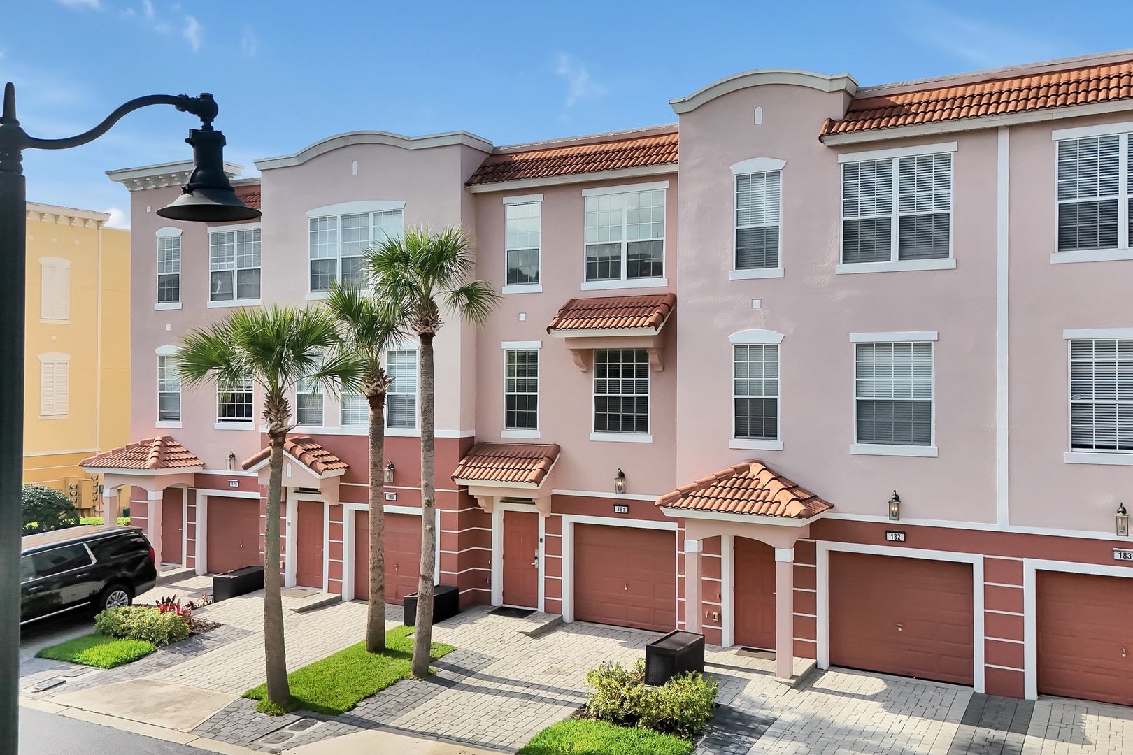 Charming townhomes with Mediterranean-style architecture featuring private garages and landscaped courtyards in a peaceful residential community.