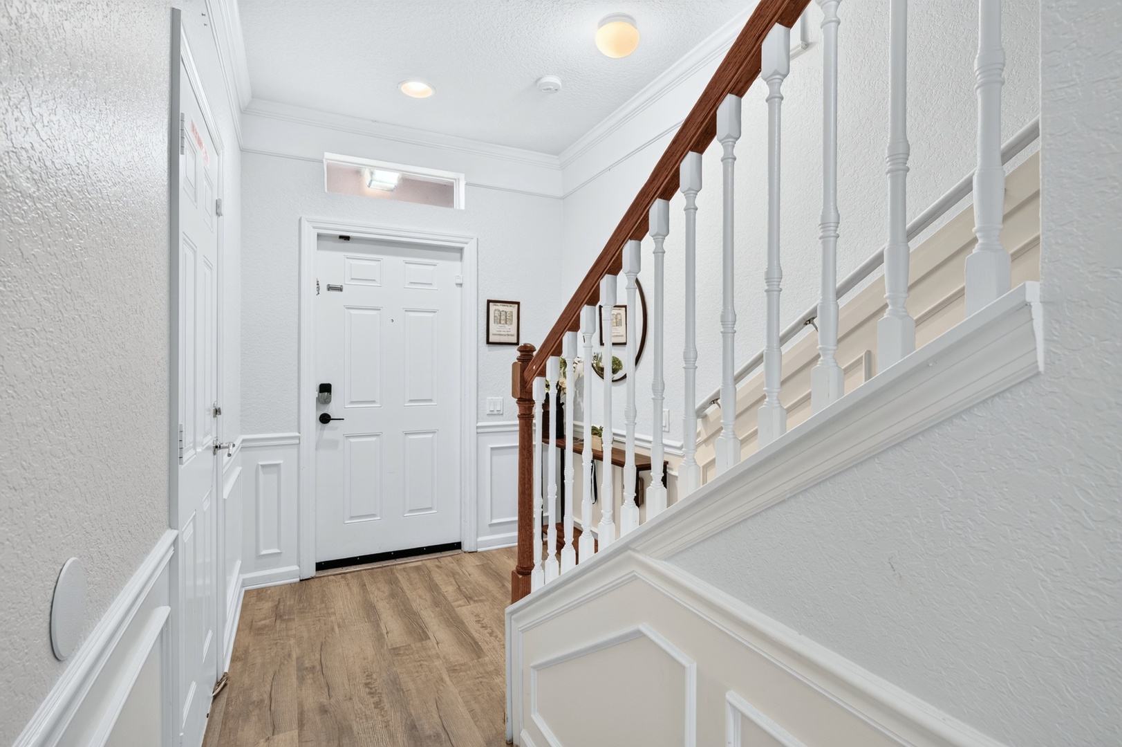 A bright, welcoming entryway greets you with warm wood floors and elegant wainscoting, leading upstairs to your private retreat.