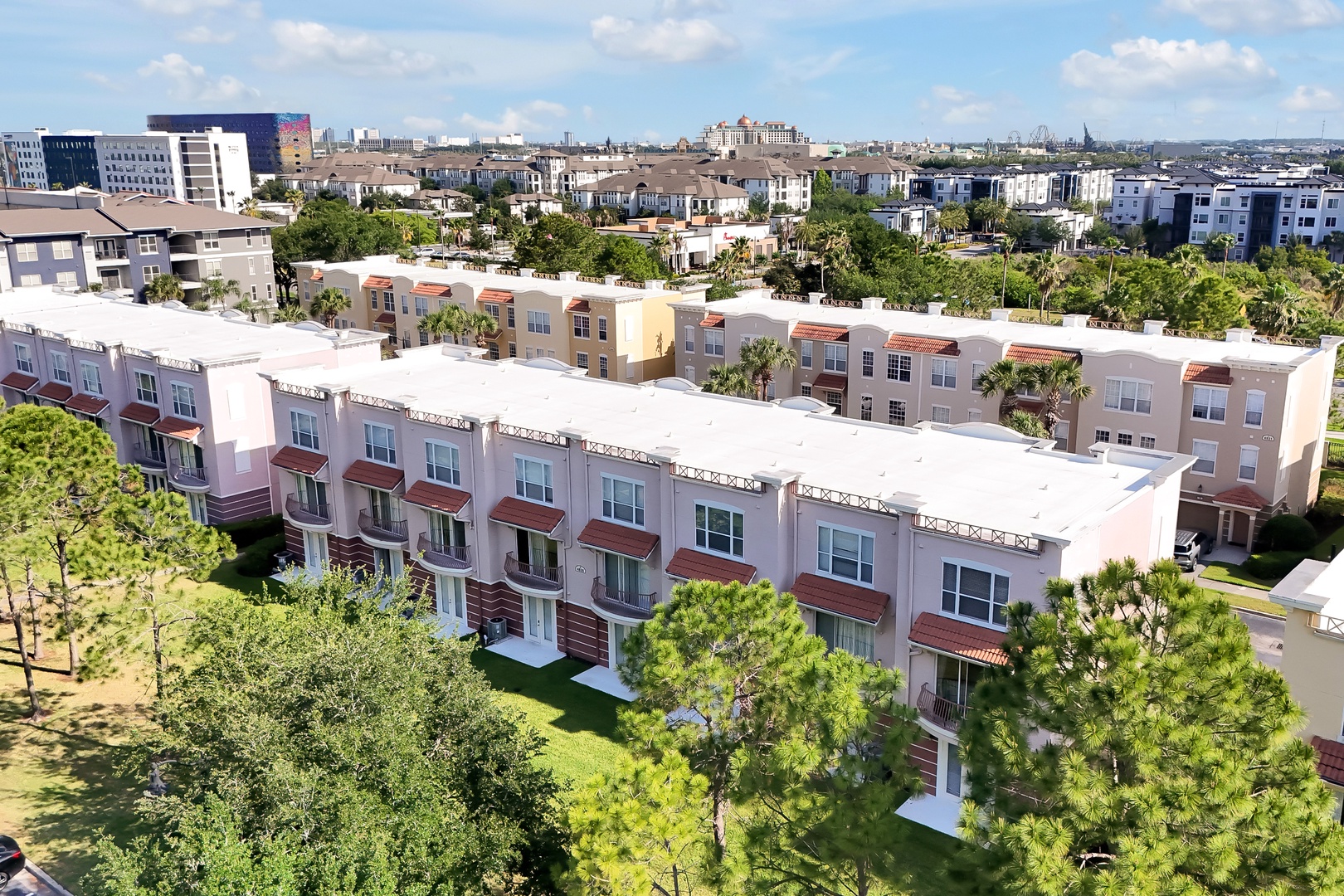 Aerial view of modern townhomes in a vibrant residential neighborhood with lush landscaping and convenient urban access.