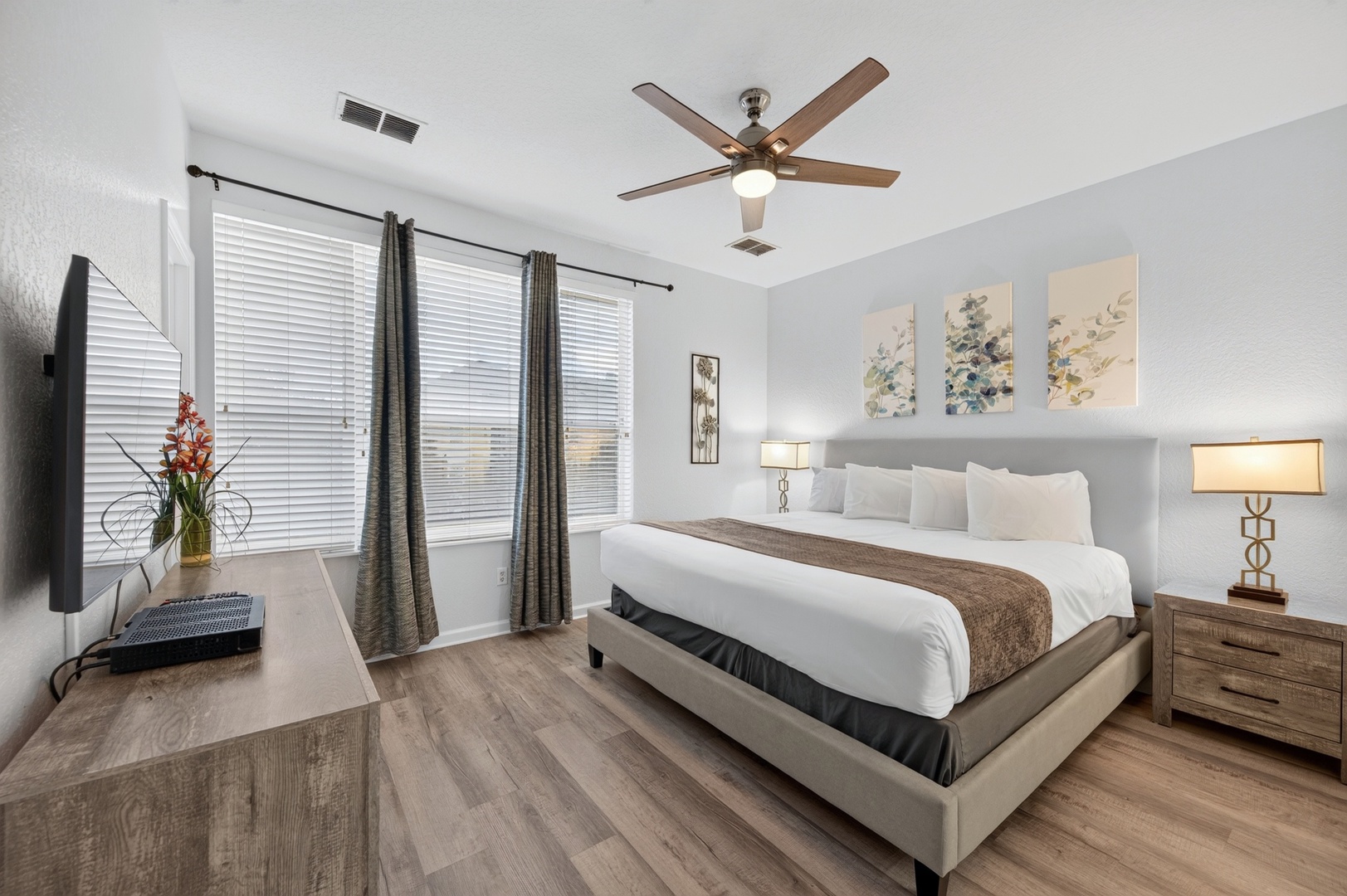 Relax in your elegantly styled bedroom, where crisp linens and warm wood tones create a serene retreat. Ceiling fan keeps you comfortable while soft natural light filters through the windows.