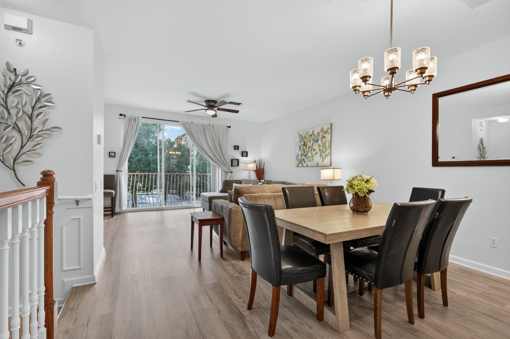 Gather around the dining table for meals, then relax in the comfortable living room as natural light pours through your private balcony doors, framing views of the lush surroundings.