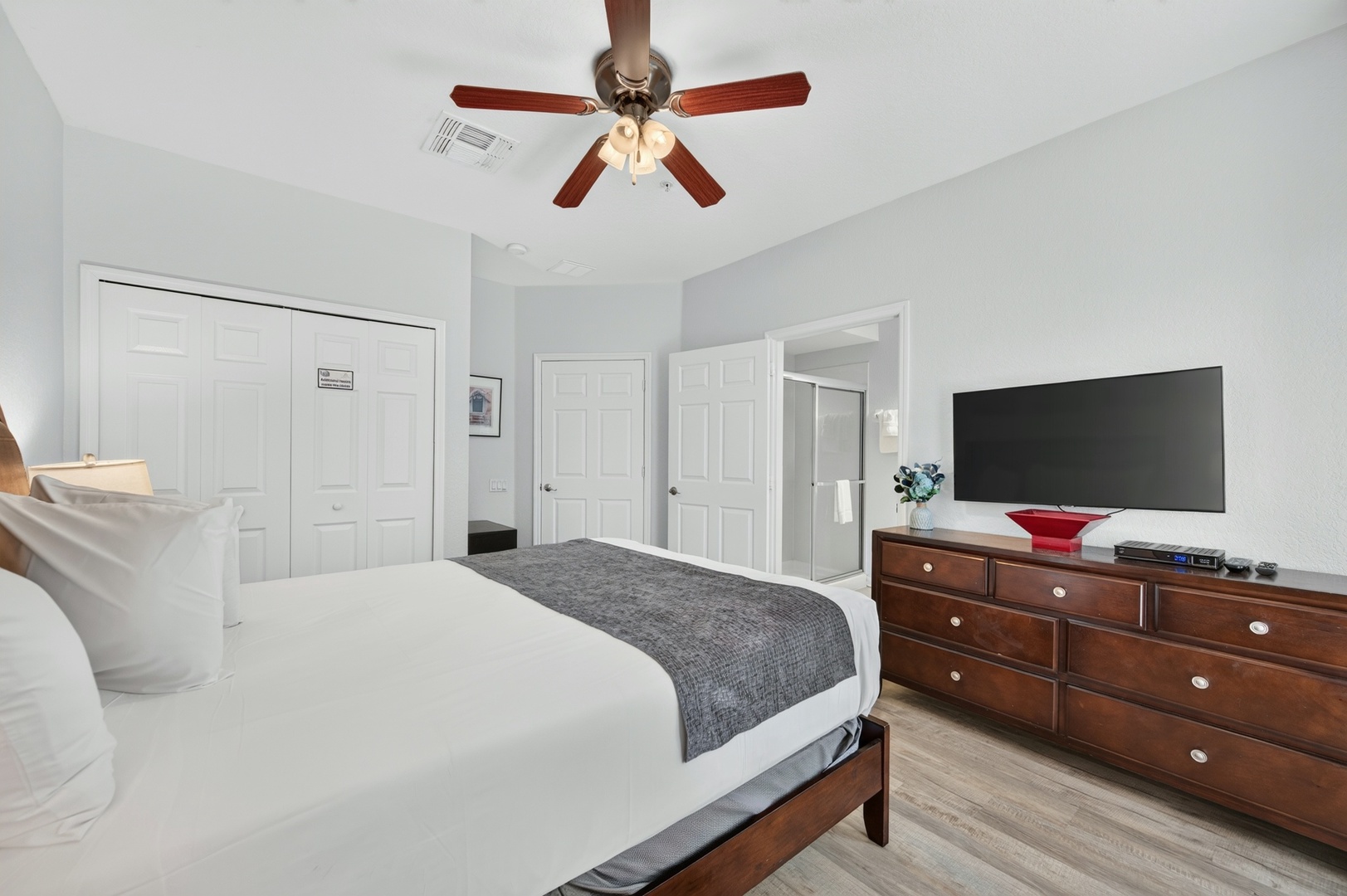 Unwind in your serene bedroom featuring a plush bed, warm wood furnishings, and a ceiling fan to keep you comfortable year-round.
