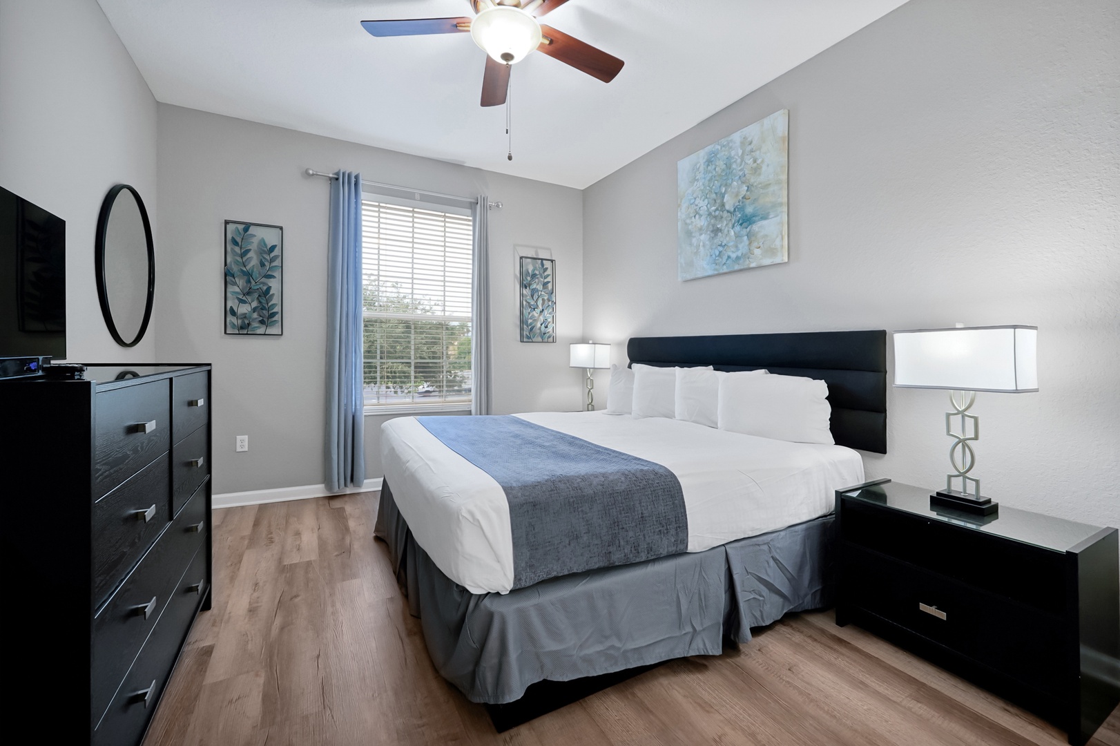 Your peaceful retreat features a plush king bed dressed in crisp linens, soft natural light filtering through sheer curtains, and thoughtful touches like bedside lamps for late-night reading.