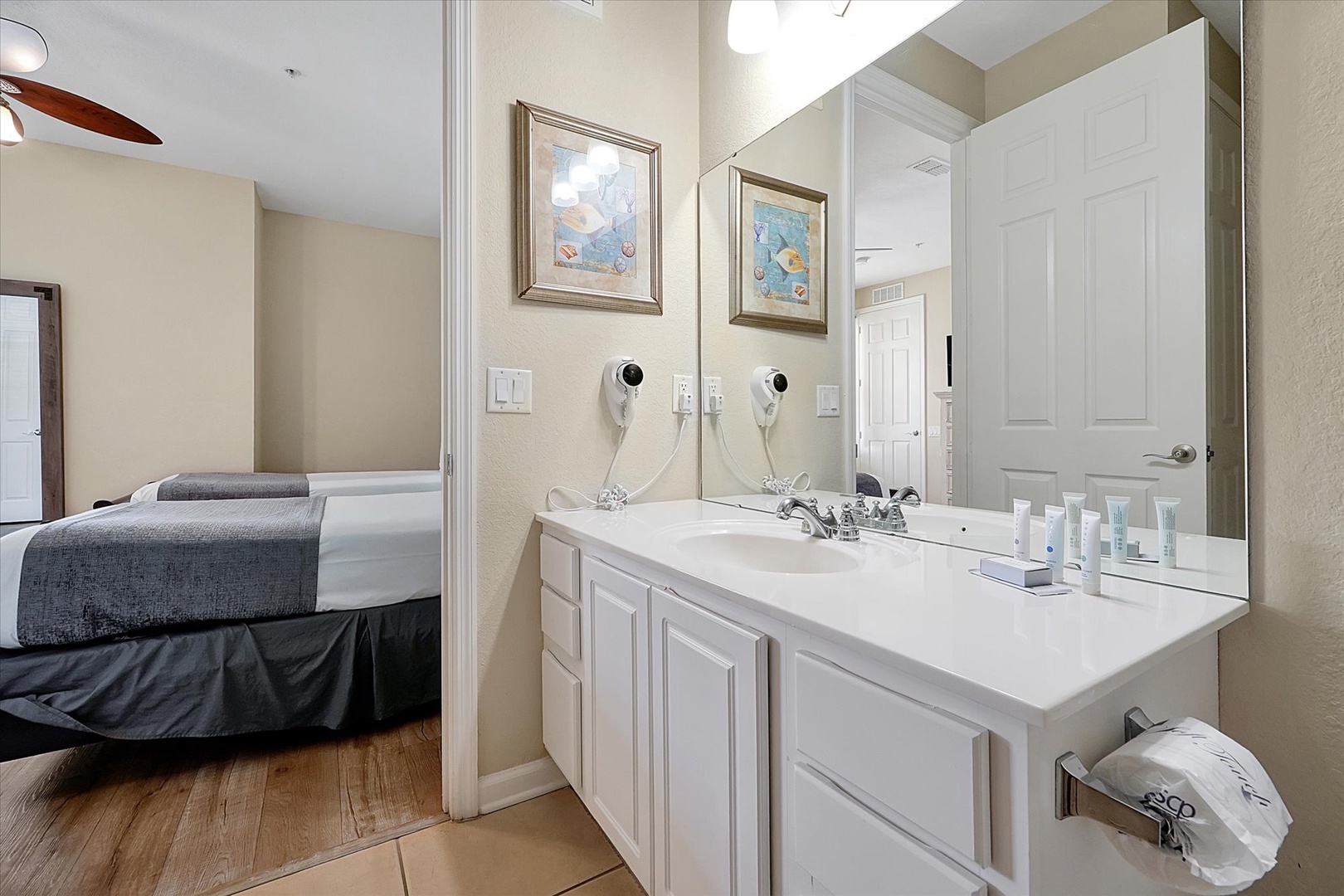 Your bright bathroom features dual sinks and thoughtful amenities, with coastal artwork adding charm to your convenient space.