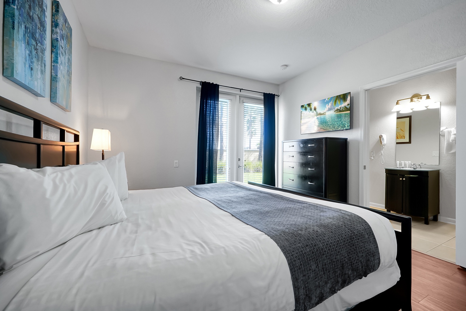 Your spacious bedroom features crisp linens and a private ensuite, with peaceful natural light streaming through sliding glass doors.