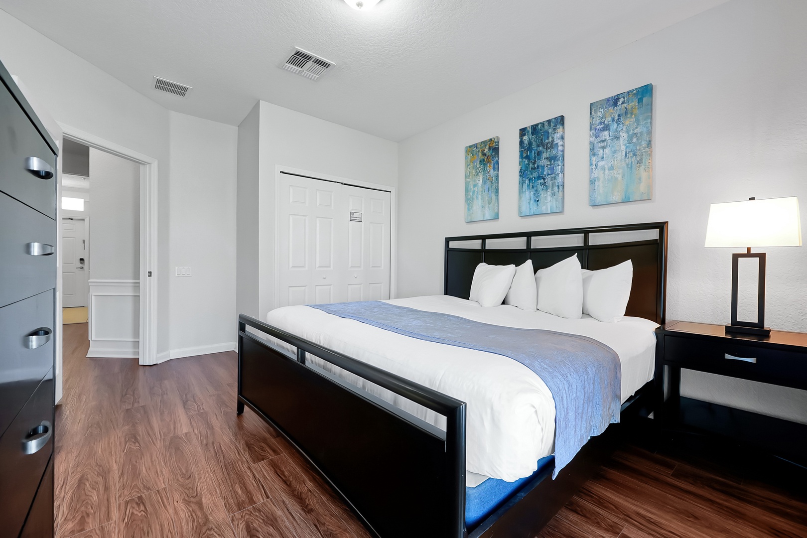 Slip into crisp white linens on your comfortable king bed, surrounded by soothing blue artwork and modern furnishings in this peaceful retreat.