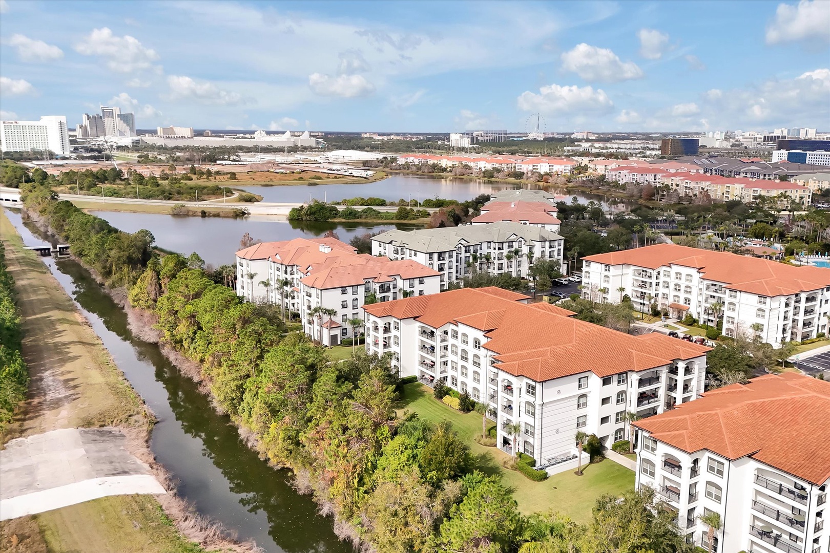 Aerial view of a resort community featuring Mediterranean-style buildings with distinctive red tile roofs nestled along scenic waterways.