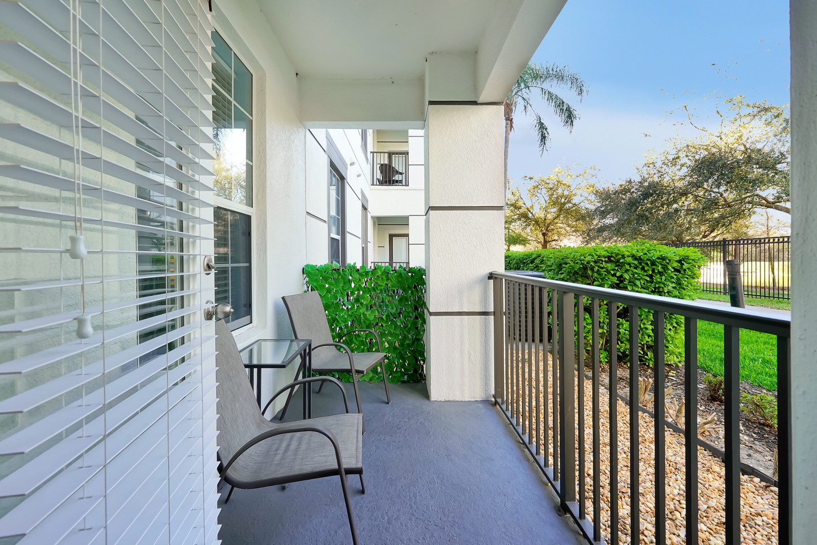 Step onto your private balcony where comfortable seating awaits, perfect for morning coffee with views of lush gardens and palm trees.