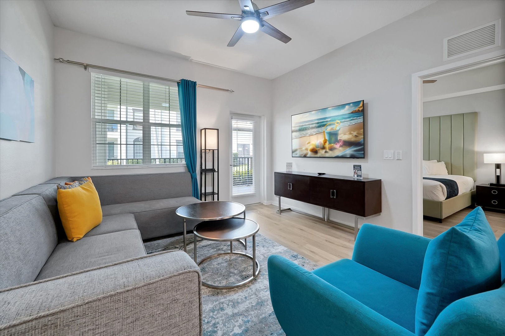 Unwind in your stylish living space with plush seating, modern entertainment center, and vibrant turquoise accents creating the perfect atmosphere for relaxation.