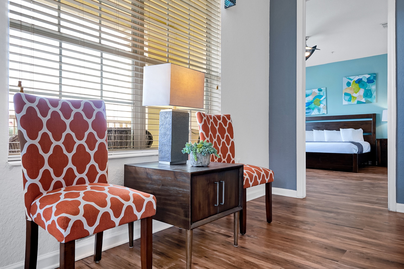 Settle into your cozy seating area, where vibrant accent chairs frame a stylish nook with natural light streaming through the blinds—your perfect spot to unwind before stepping into the bedroom.