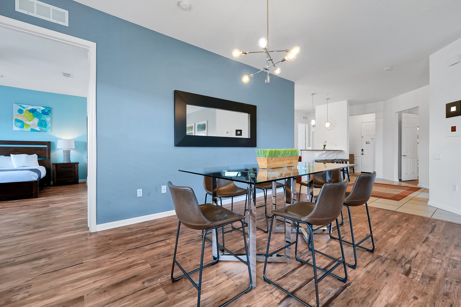 Gather around this sleek dining space where modern style meets comfort. The calming blue accent wall and warm wood floors create an inviting atmosphere for your morning coffee or evening meals with loved ones.