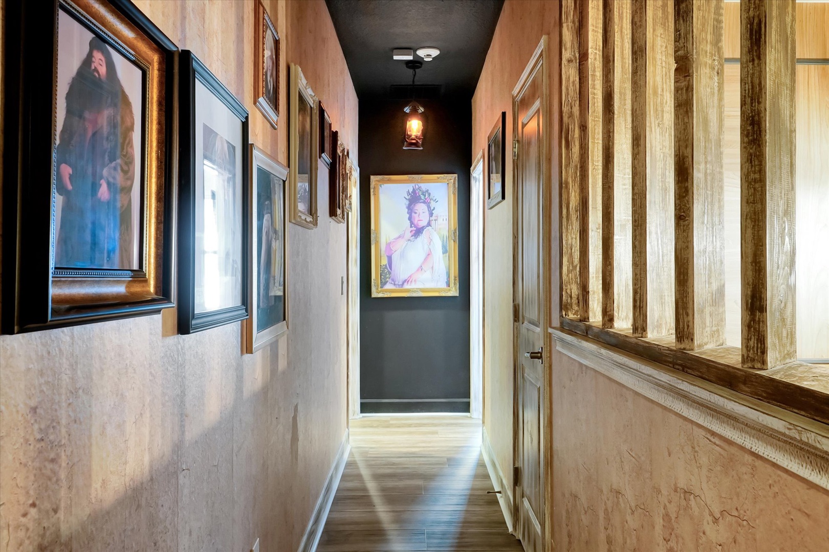 Step into an artfully designed hallway where curated paintings and warm pendant lighting guide your way, blending rustic wood textures with modern elegance.