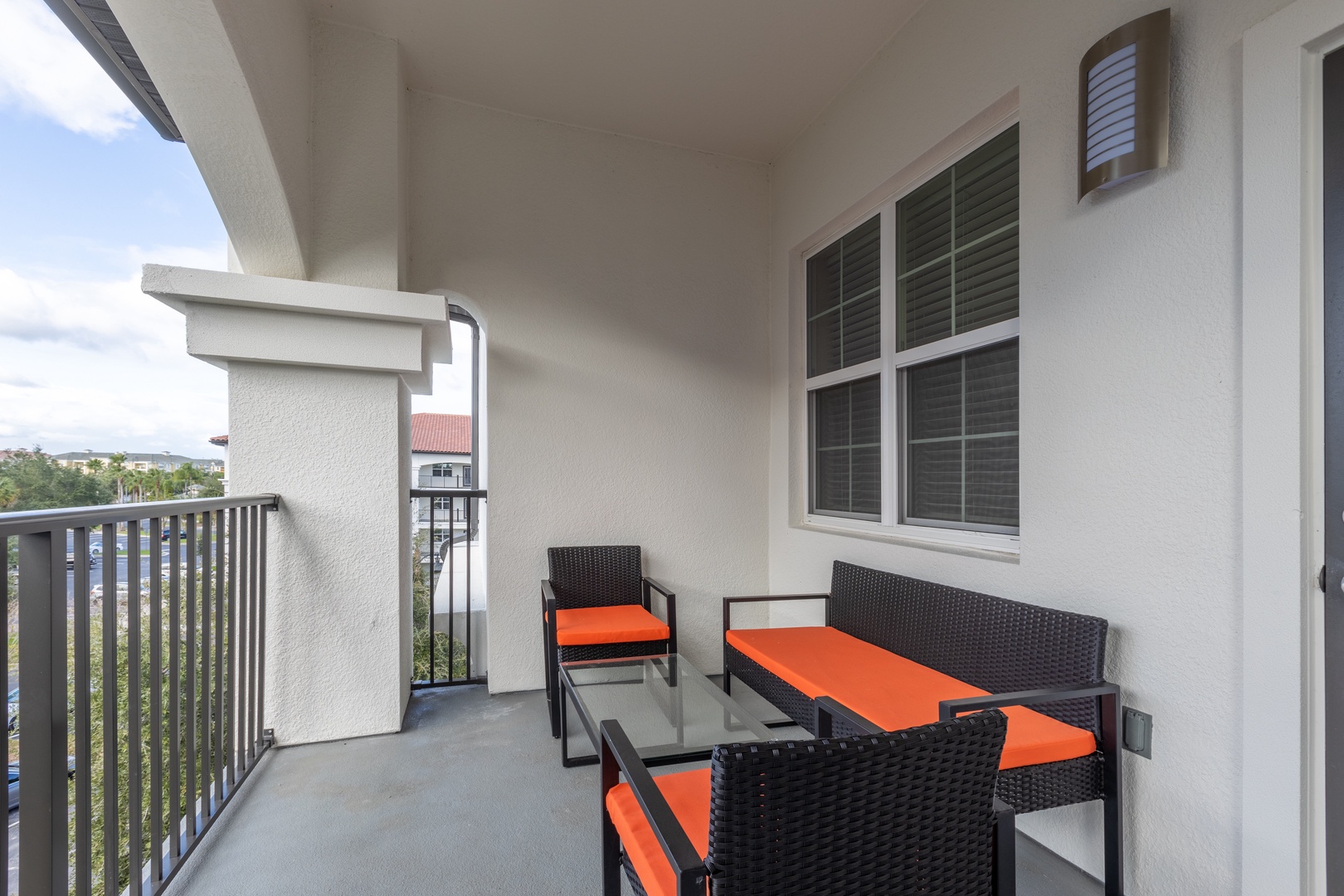 Your private balcony offers comfortable seating where you can unwind with vibrant orange cushions and scenic neighborhood views.