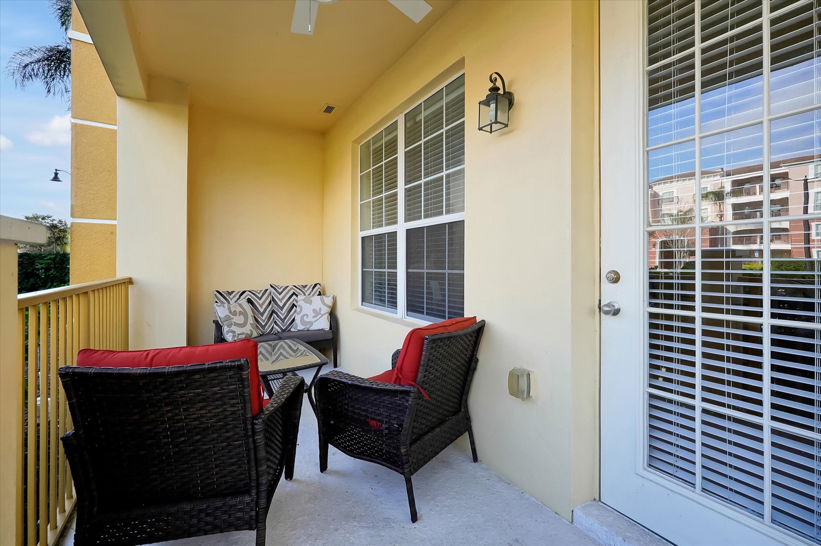 Your private balcony beckons with comfortable wicker seating and plush red cushions, perfect for morning coffee or evening relaxation.