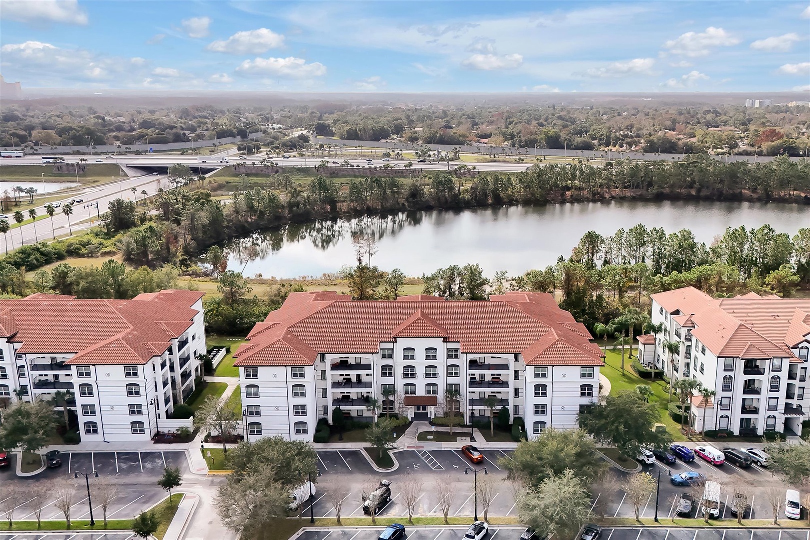 Lakefront apartment complex surrounded by lush greenery and scenic water views in a peaceful residential setting.