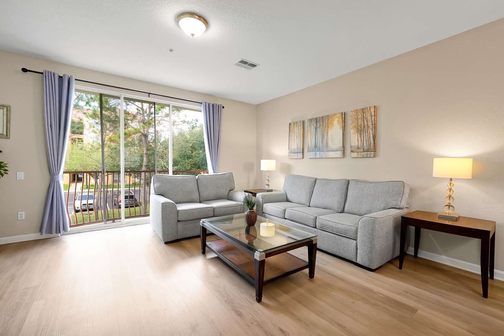 Relax in your bright living room with comfortable seating, natural light streaming through sliding doors to your private balcony.