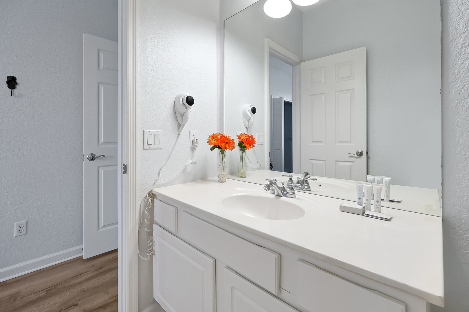 Your bright bathroom features a spacious vanity with hair dryer and fresh flowers, creating a welcoming start to your day.