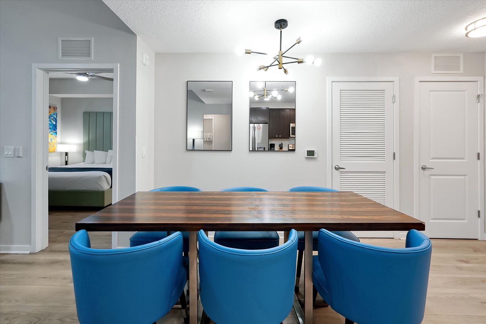 Your elegant dining space features a rich wood table and vibrant blue chairs, perfect for gathering with loved ones under the stylish chandelier.
