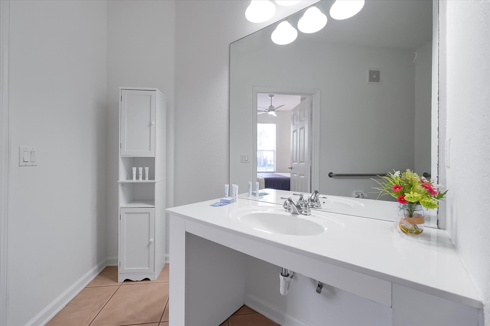 Fresh white bathroom with vanity lighting and thoughtful touches like flowers to brighten your morning routine.