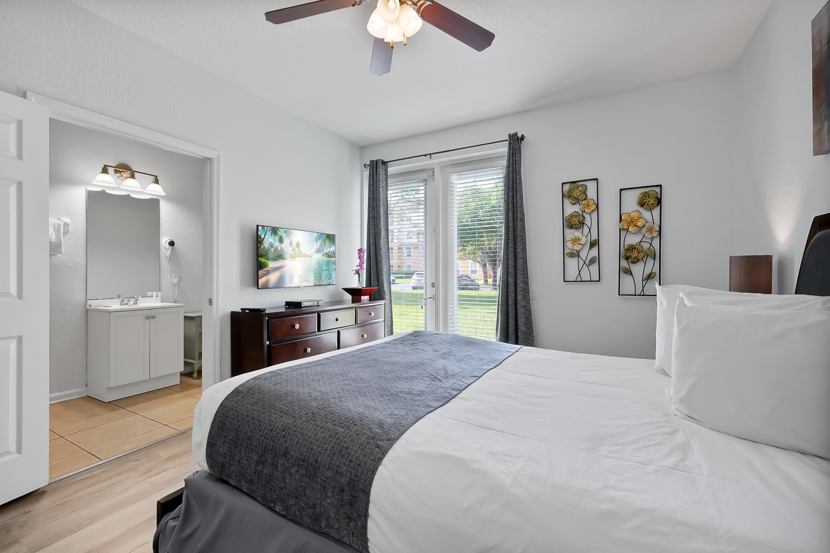 Relax in your bright bedroom with plush bedding, modern amenities, and peaceful garden views through sliding doors.