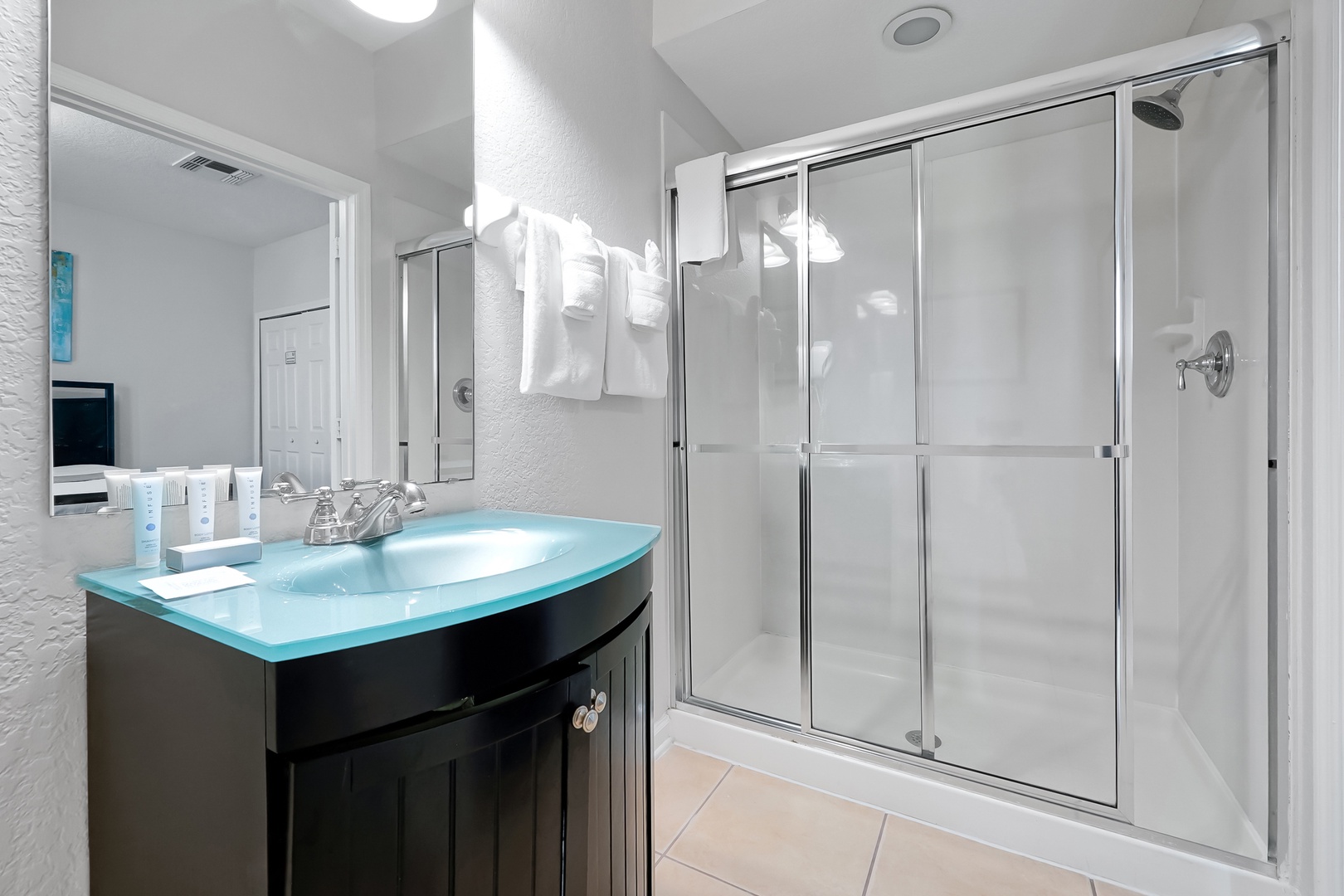 Your pristine bathroom features a modern glass shower and sleek vanity with stunning turquoise countertop for ultimate relaxation.
