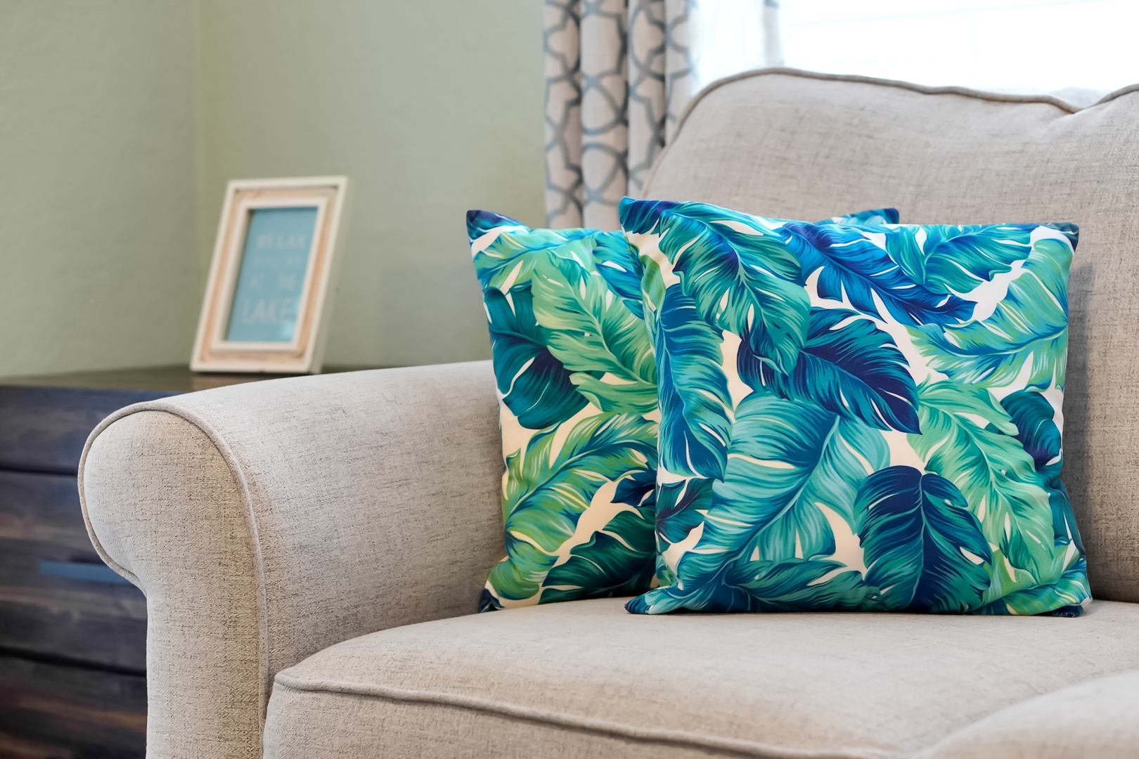 Sink into this cozy armchair with tropical pillows and let your vacation mindset bloom in this thoughtfully designed living space.