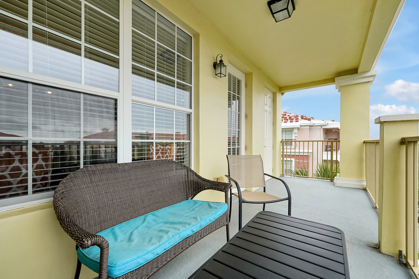 Step out onto your private balcony and settle into comfortable seating with morning coffee or evening relaxation. The covered space offers a peaceful retreat with views of the neighboring rooftops and open sky.