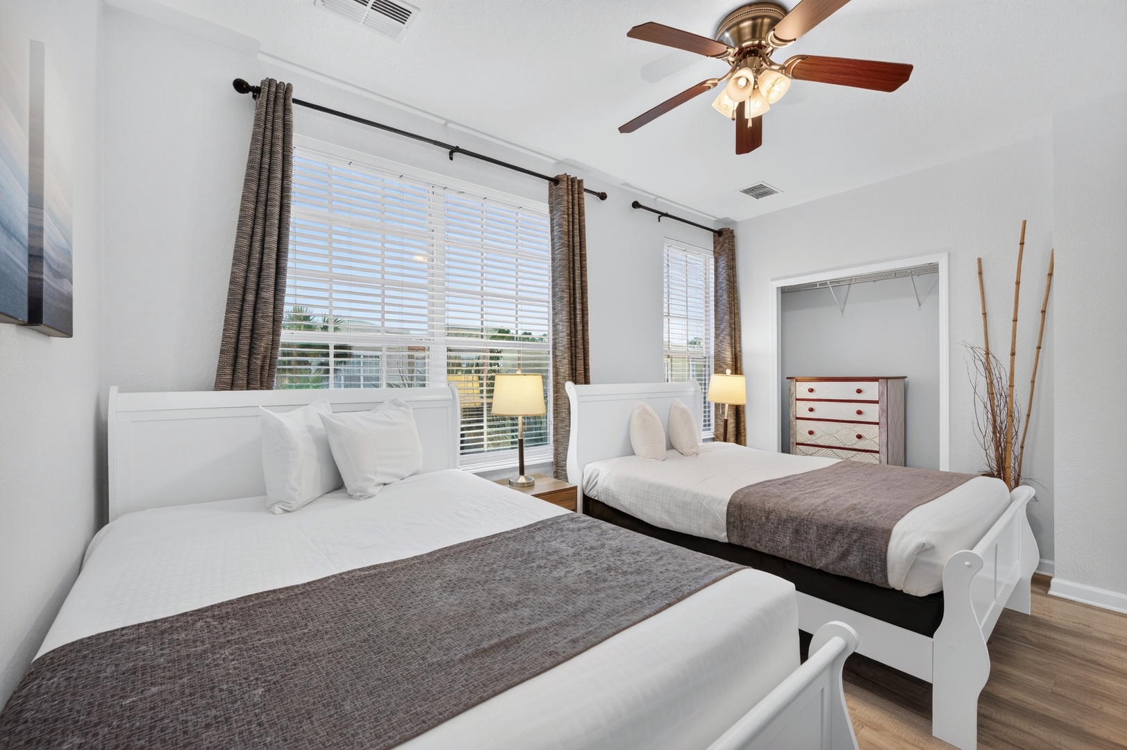 Unwind in your serene bedroom, where two plush beds await under a gentle ceiling fan. Soft natural light filters through the windows, creating a peaceful retreat for restful nights.
