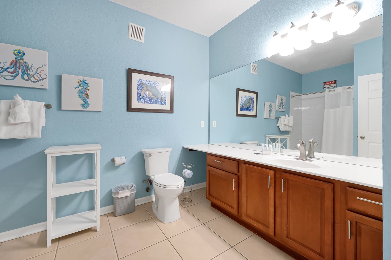 Refresh in your bright coastal bathroom with ocean-themed artwork and spacious vanity for getting ready each morning.