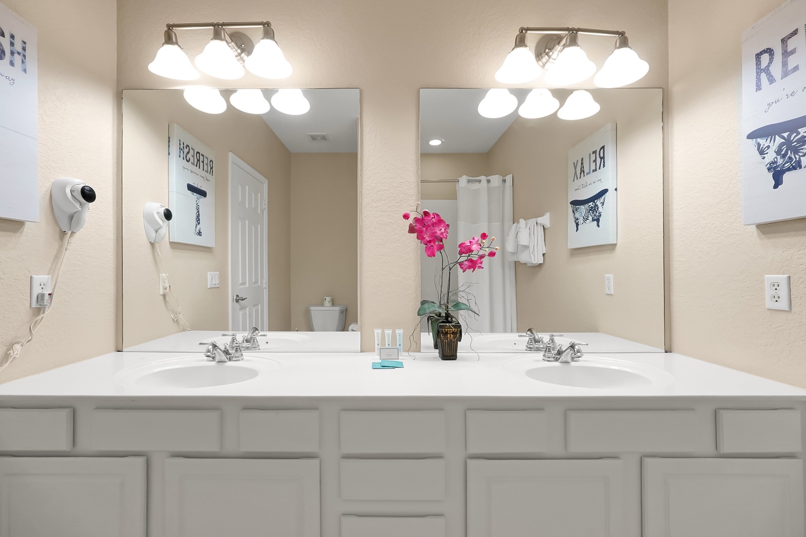 Your spacious dual-sink vanity offers plenty of room to get ready, with bright Hollywood-style lighting and fresh orchids adding elegance.