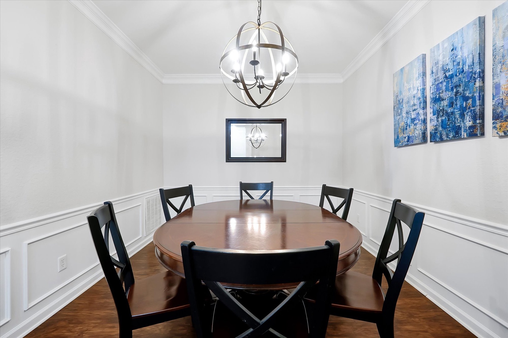 Gather around your elegant round dining table for memorable meals in this beautifully appointed space with stunning artwork and warm lighting.