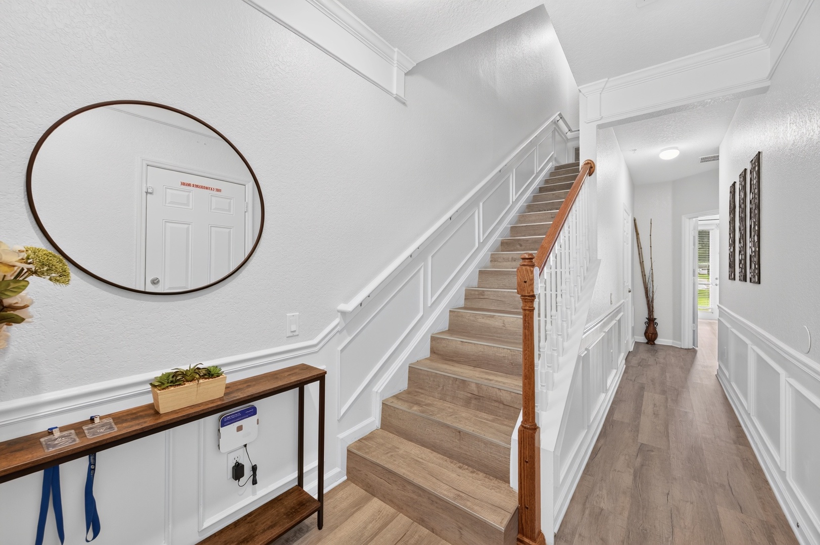 Bright, airy entryway welcomes you with elegant wainscoting, a wide staircase, and warm wood tones—your fresh start to feeling at home.