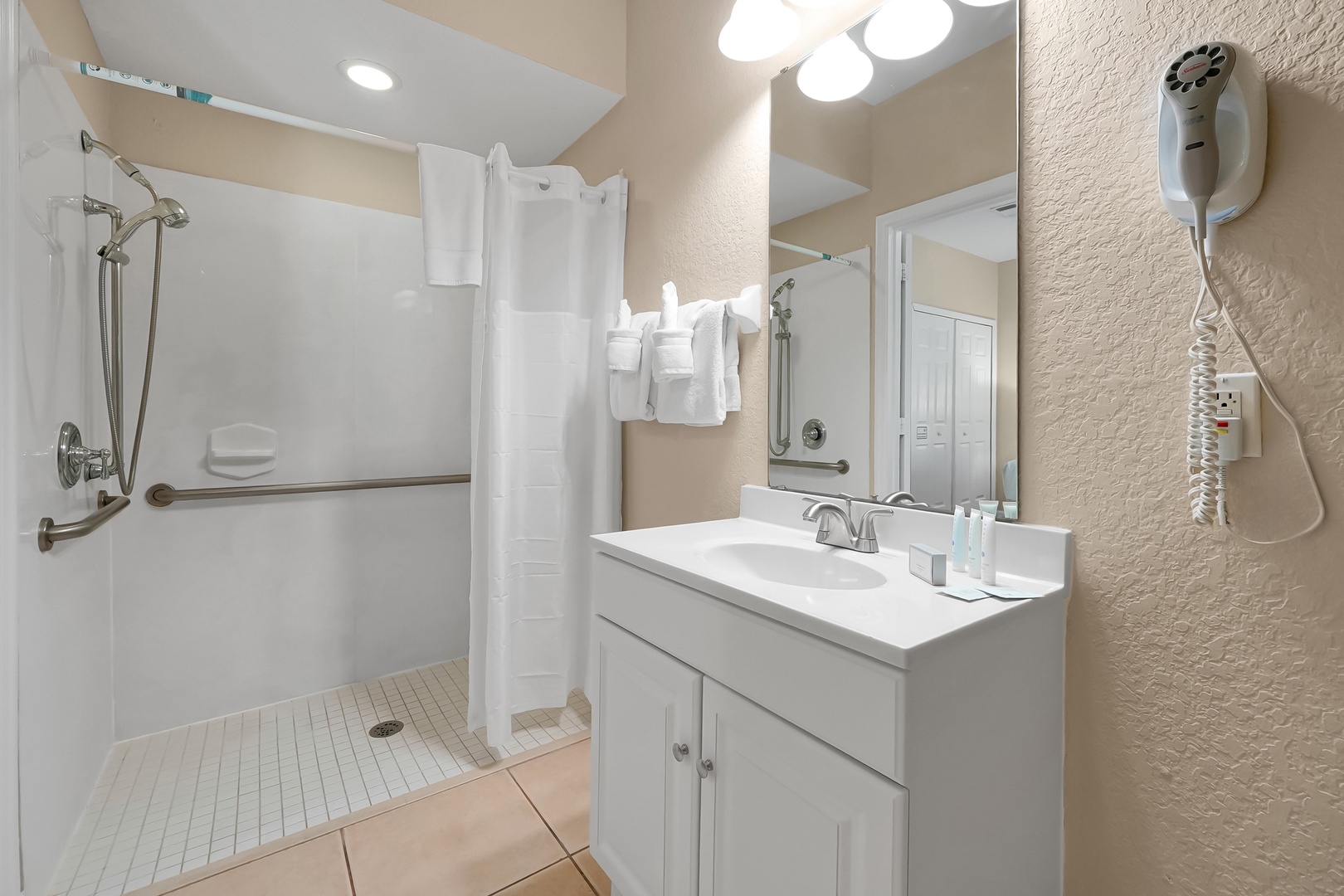 Your accessible bathroom features a spacious roll-in shower with grab bars, fresh towels, and convenient amenities for a comfortable stay.