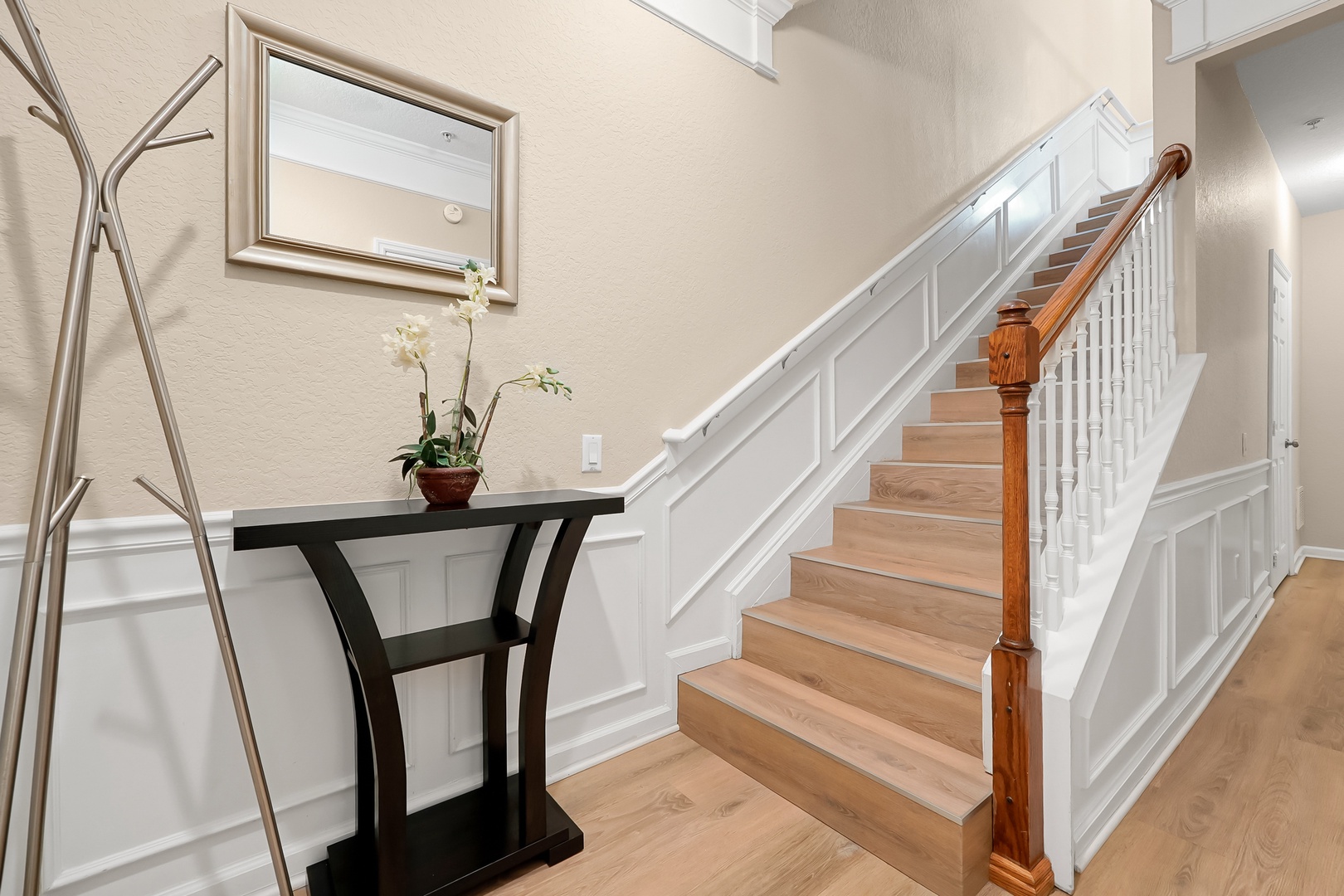 Step into your elegant entryway with gleaming hardwood floors and classic wainscoting that welcomes you home.