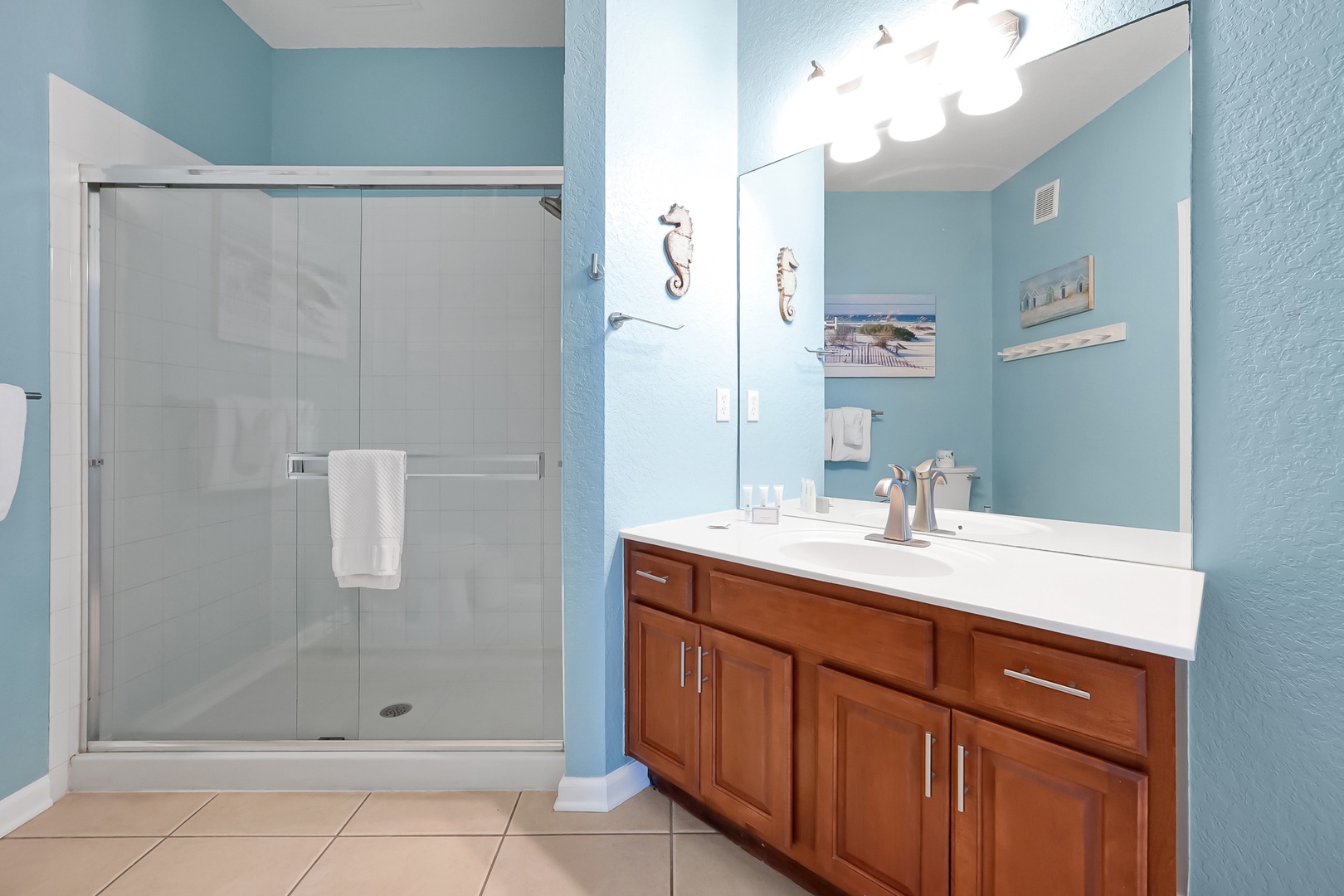 Step into your serene bathroom oasis with coastal blue walls, spacious walk-in shower, and elegant vanity for refreshing morning routines.