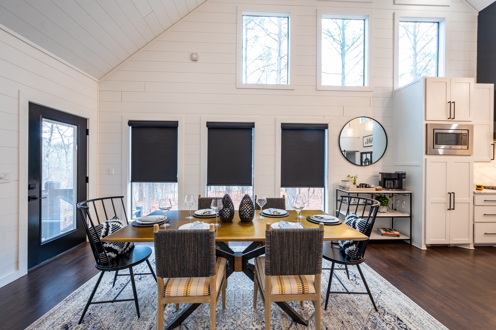 Dining table is surrounded by large windows and beautiful forest views