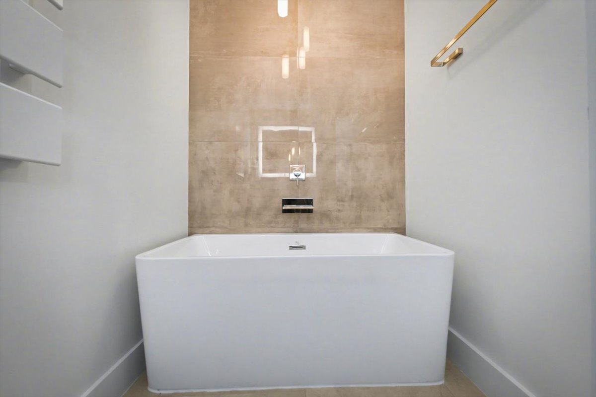 Unwind in your sleek modern bathtub, where warm lighting and marble create the perfect spa-like sanctuary for relaxation.