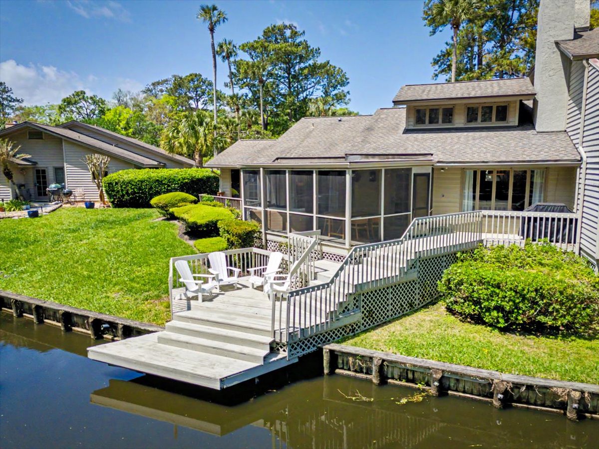 Waterfront property featuring screened porch, private dock, and manicured gardens in a peaceful canal-side setting.