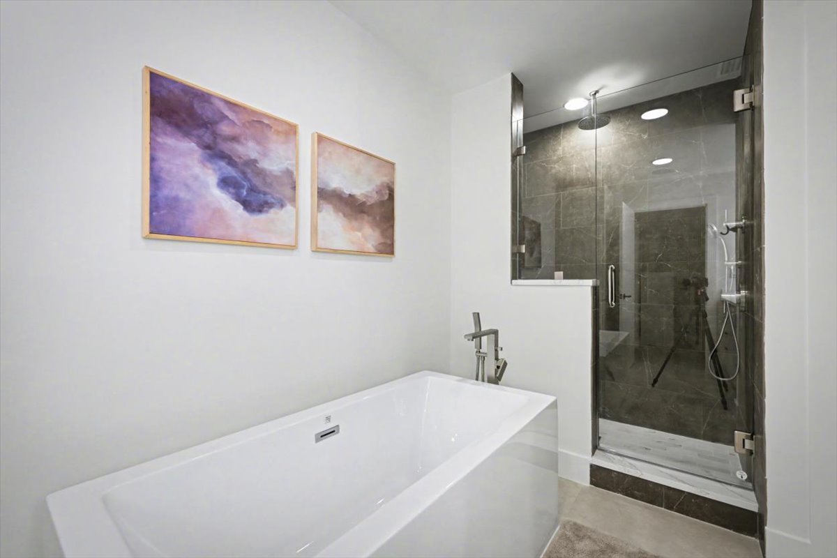 Unwind in your luxurious bathroom featuring a deep soaking tub and elegant walk-in shower with rainfall head.