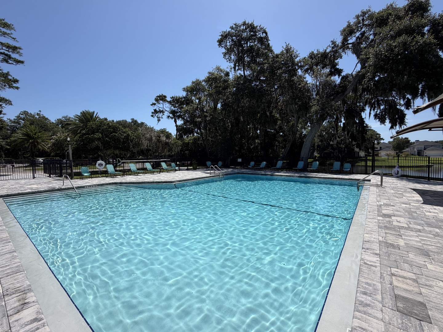 Slip into the sparkling pool beneath towering oaks draped in Spanish moss. Lounge on the sundeck or cool off in the crisp, clear water—your perfect day awaits under blue skies.