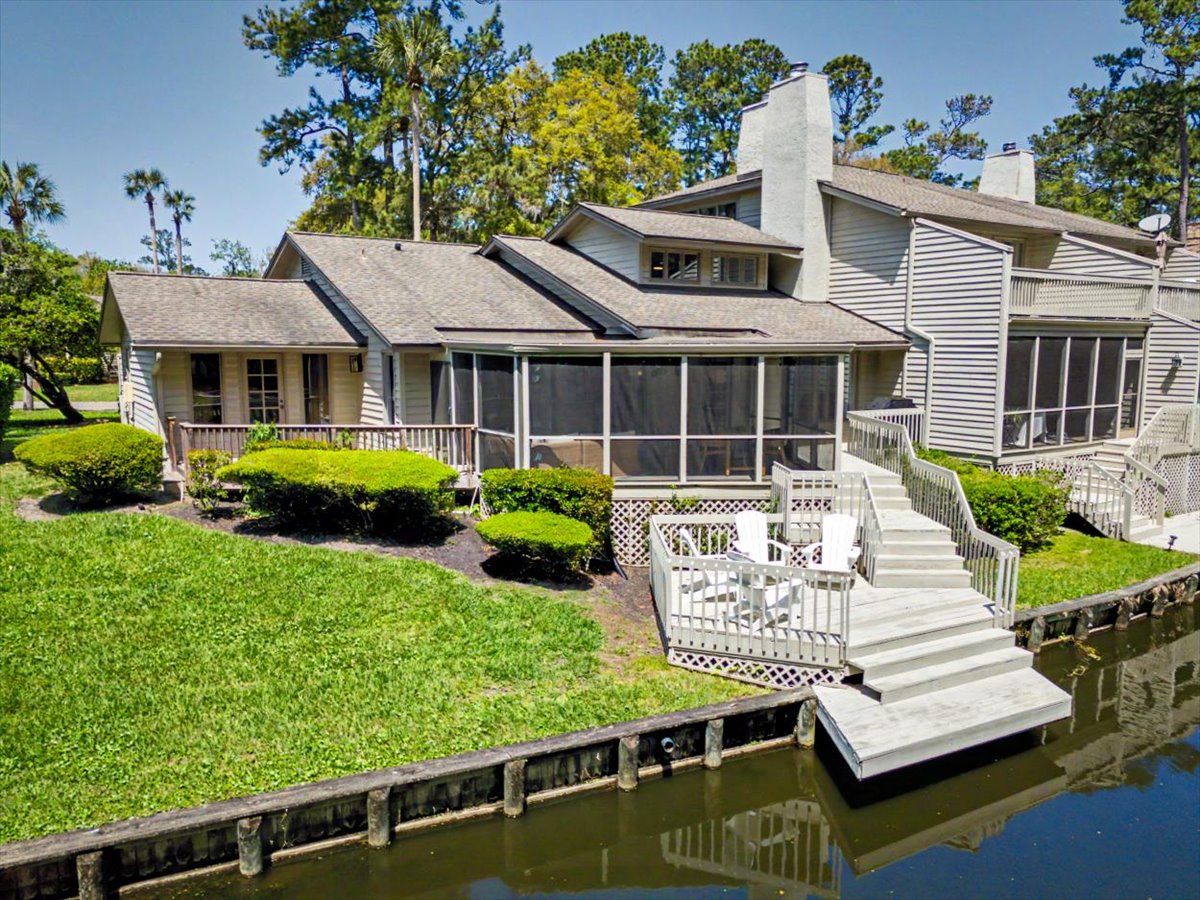 Waterfront vacation rental featuring a private dock and screened porch, surrounded by lush landscaping in a peaceful lagoon setting.