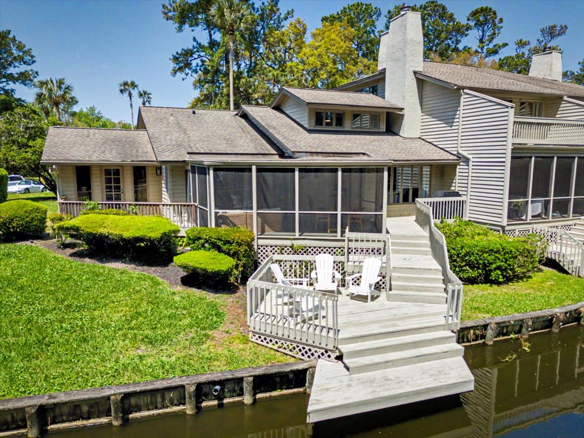 Waterfront property with private dock and screened porch, surrounded by lush landscaping and mature trees in a peaceful canal setting.