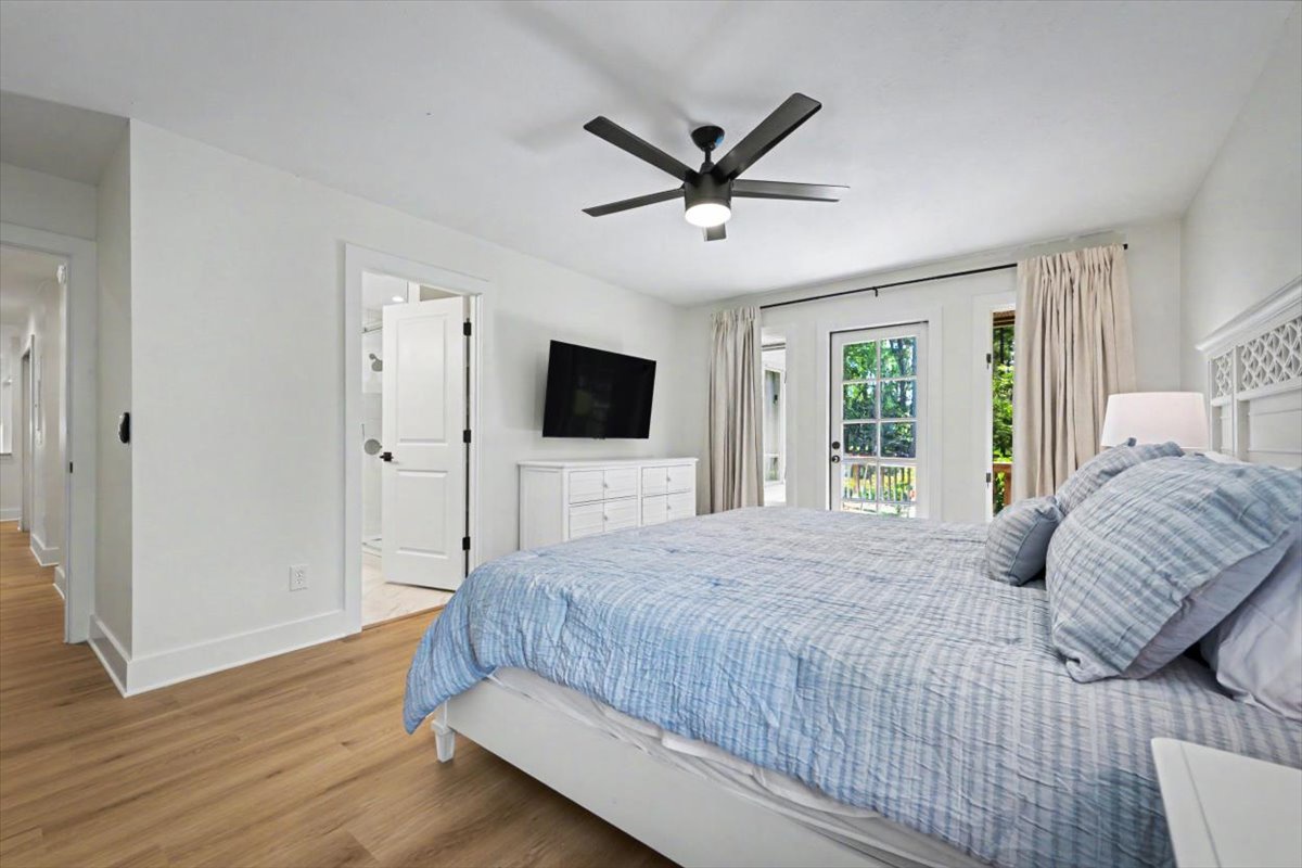 Unwind in your spacious bedroom featuring soft blue linens, warm hardwood floors, and French doors opening to your private balcony.