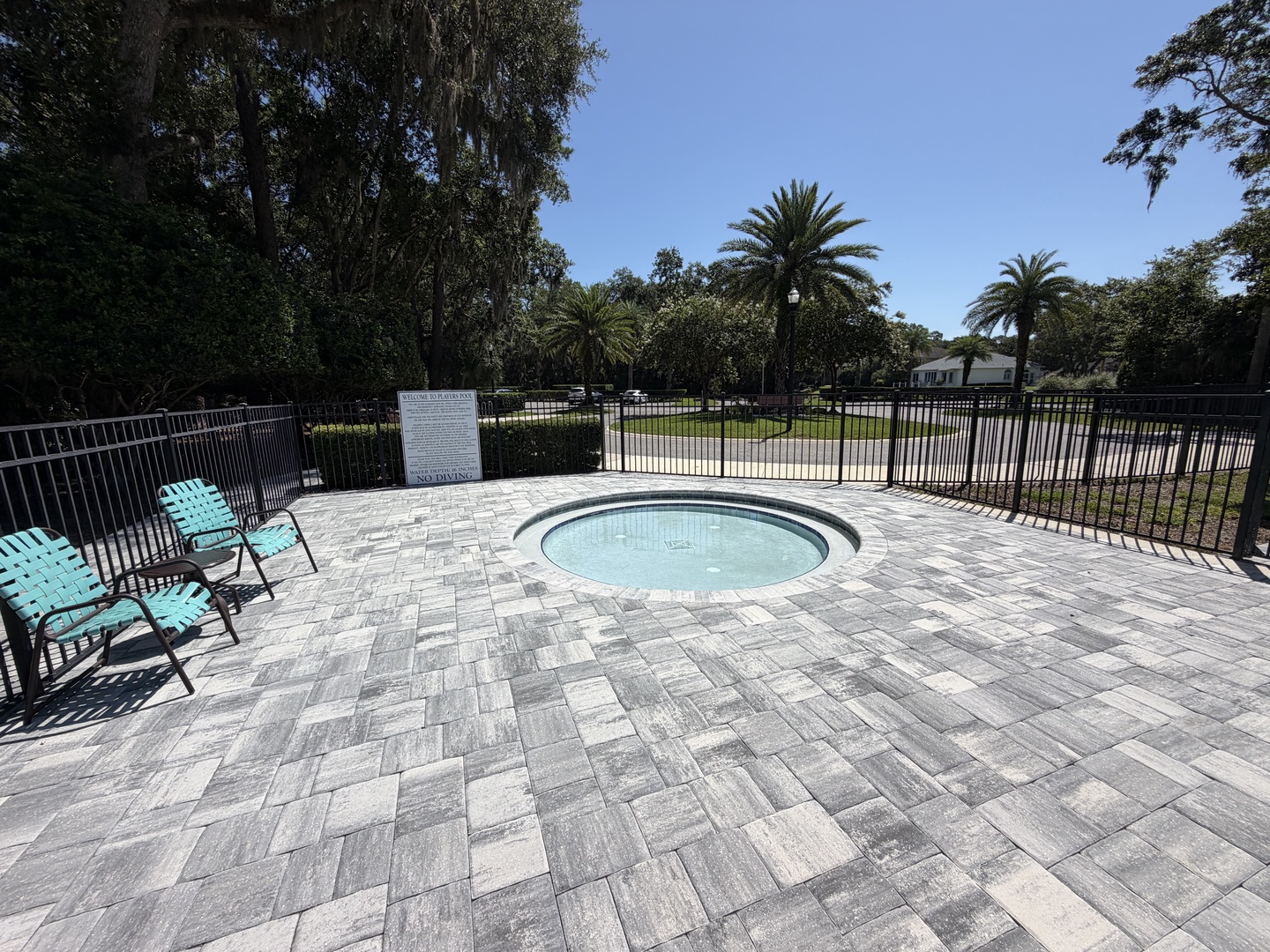 Soak your worries away in this inviting hot tub, nestled within a spacious paver deck framed by lush palm trees and peaceful gardens.