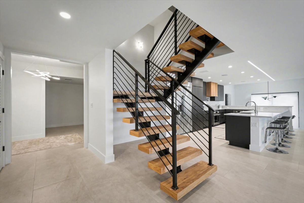 Stunning modern staircase with sleek wood steps leads to your upper-level retreat, while the chef's kitchen awaits culinary adventures.