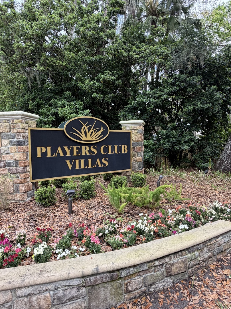 Players Club Villas entrance sign surrounded by colorful flowers and lush landscaping creates an elegant arrival experience.