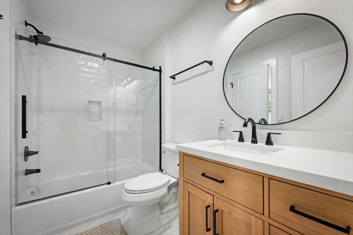 Refresh in your beautifully designed bathroom with modern fixtures, sleek glass shower, and warm wood vanity.
