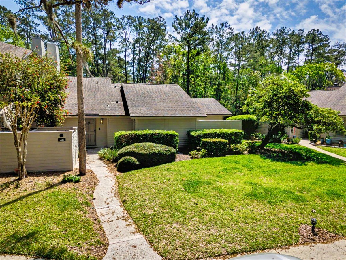 Charming single-story home nestled among towering pines with manicured landscaping and peaceful wooded surroundings.