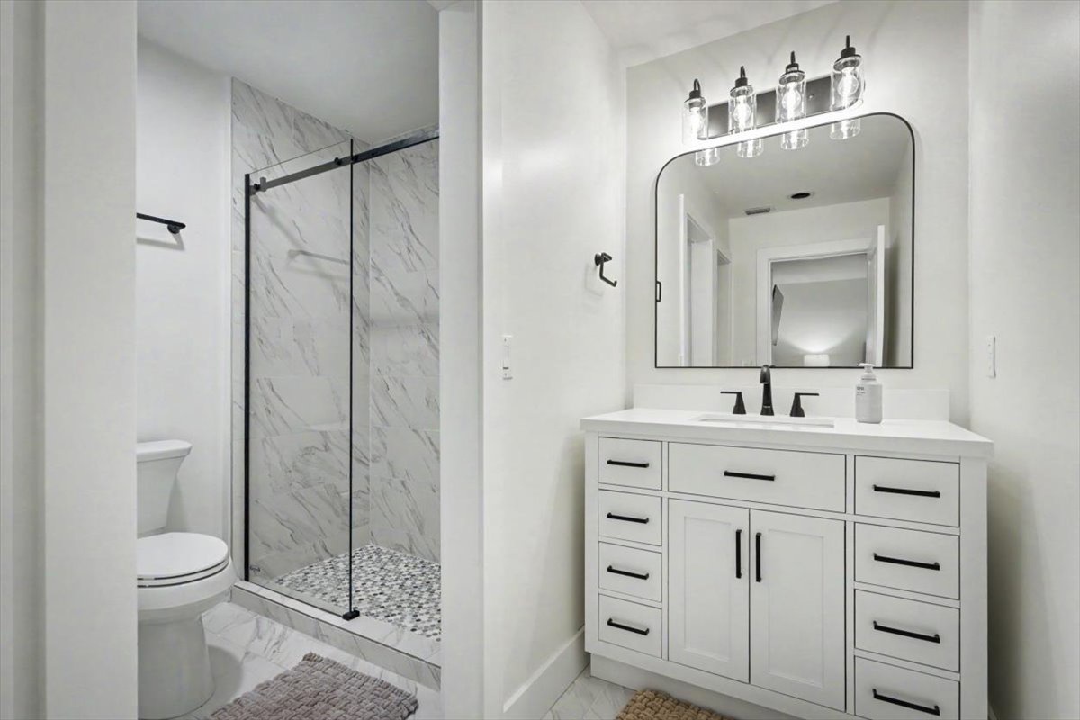 Your elegant bathroom features a stunning marble-tiled shower and spacious vanity with ample storage for all your essentials.